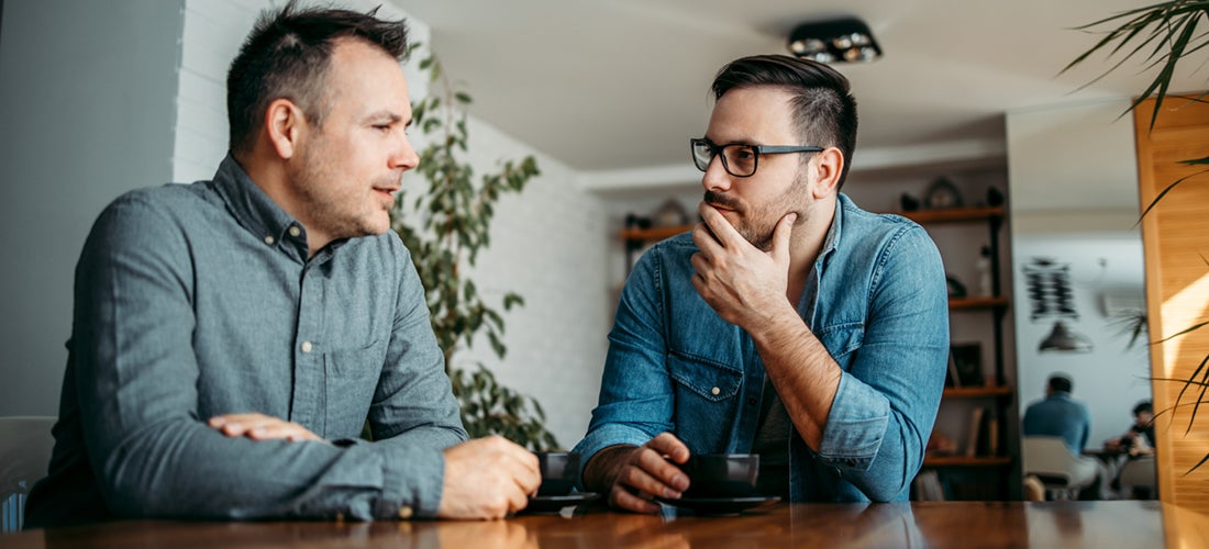 Två män som sitter och diskuterar vid ett bord.