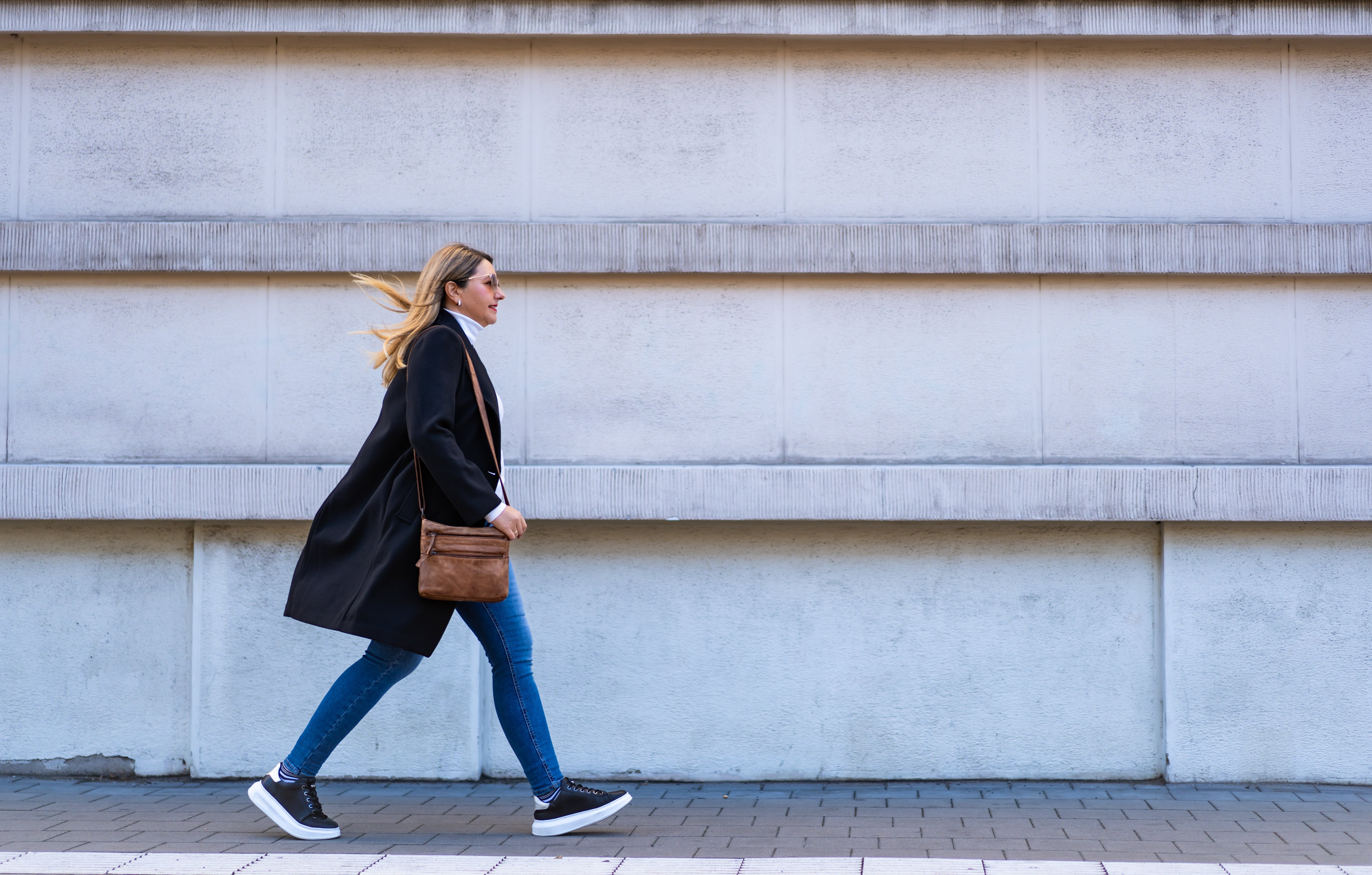 Kvinna som går framför betongvägg.