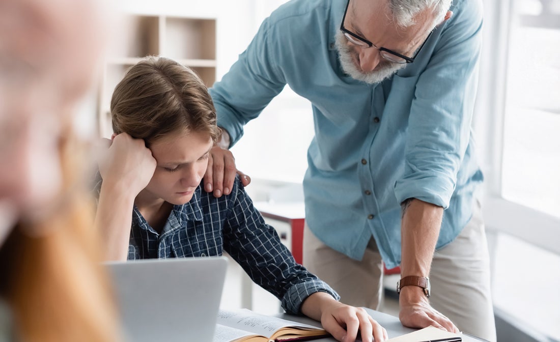 Elev och lärare vid skolbänk i skolan