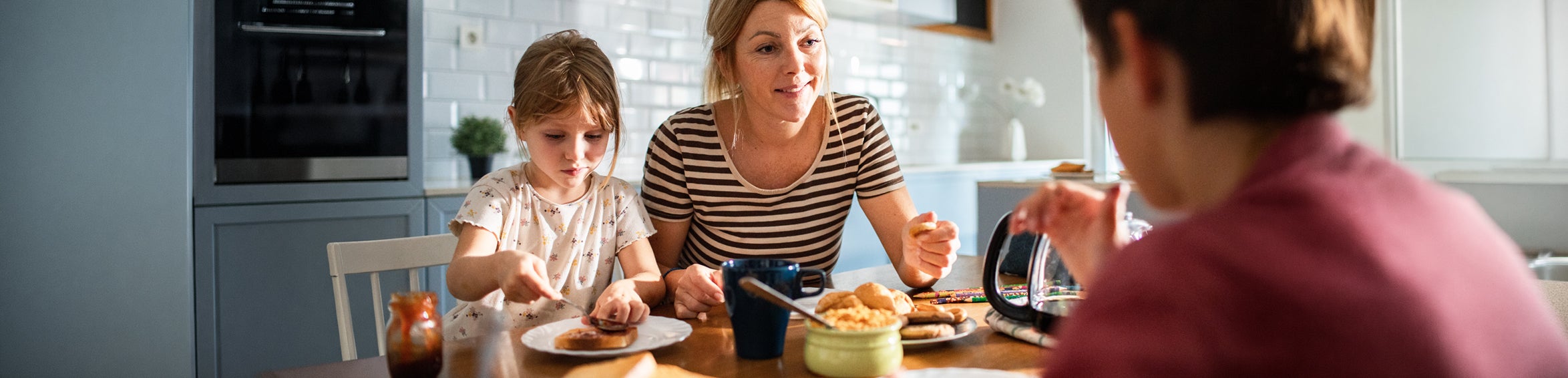 Mamma äter frukost med sina barn på köksbordet