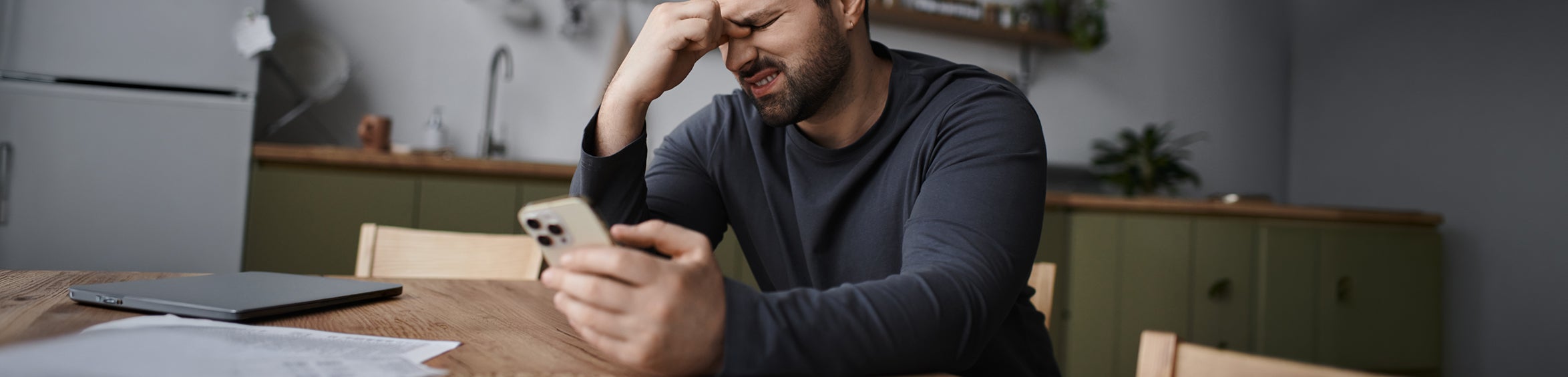 Stressad man granskar dokument och kollar sin telefon.