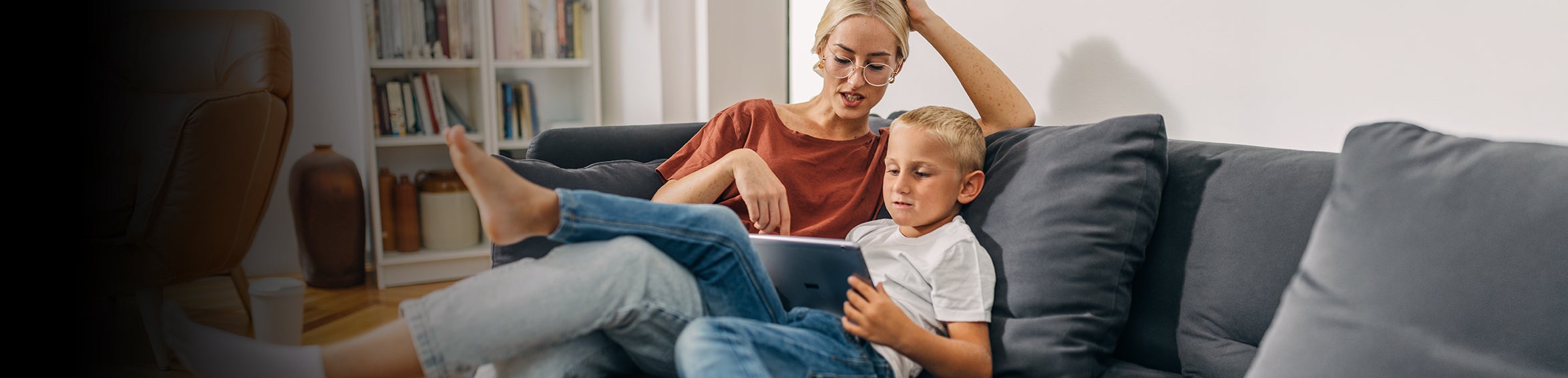 Mamma och son sitter i soffan och tittar på en läsplatta